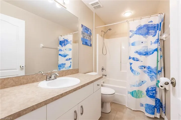 Full bath featuring tile patterned floors, toilet, vanity, shower / bath combo
