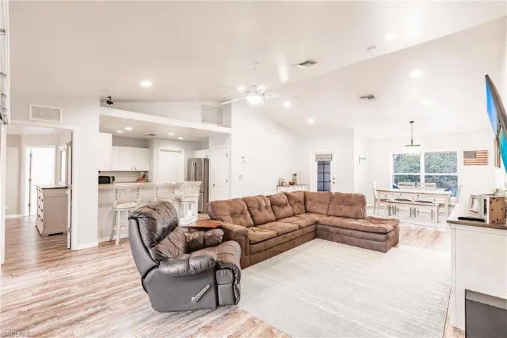 Living room featuring vaulted ceiling, recessed lighting, light wood finished floors, and a ceiling fan