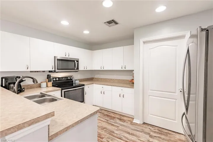 Kitchen featuring light countertops, light wood-style flooring, appliances with stainless steel finishes, and a sink