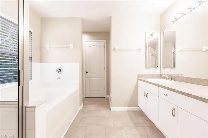 Full bath with baseboards, a garden tub, tile patterned floors, and vanity