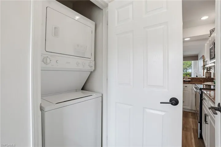 Laundry area featuring stacked washer / dryer, dark wood-type flooring, and recessed lighting