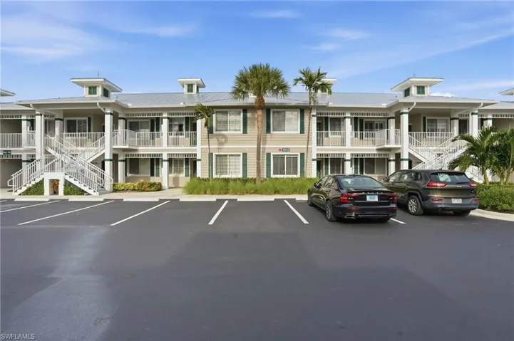 View of property with stairs and uncovered parking
