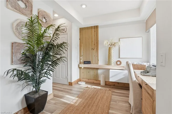 Hall featuring light wood finished floors, a raised ceiling, and recessed lighting