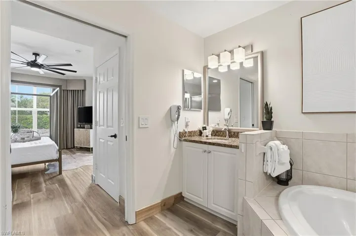 Full bathroom with ensuite bath, vanity, light wood finished floors, and a garden tub
