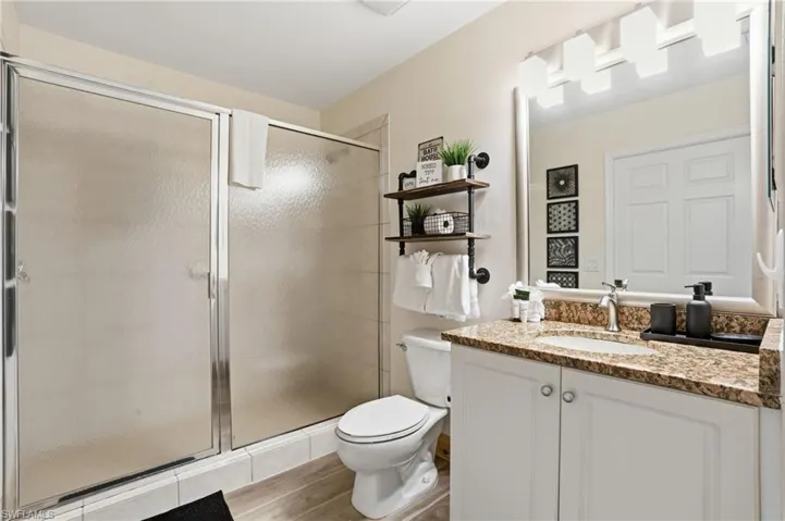 Full bathroom featuring vanity, a shower stall, and light wood-style flooring