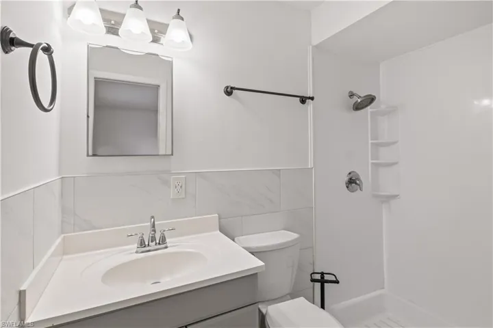 Bathroom featuring vanity, a shower stall, and tile walls
