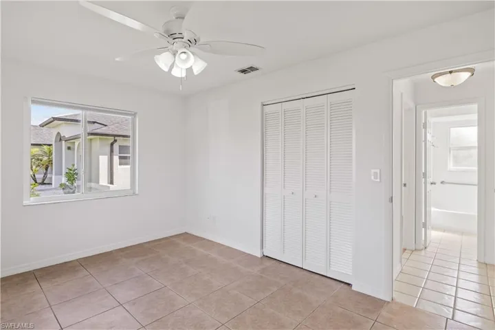 Unfurnished bedroom featuring light tile patterned flooring, a closet, a ceiling fan, and multiple windows