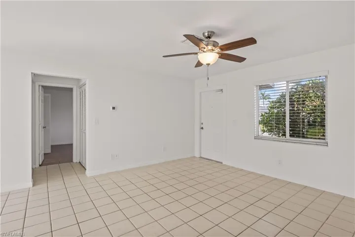 Empty room with ceiling fan and light tile patterned floors