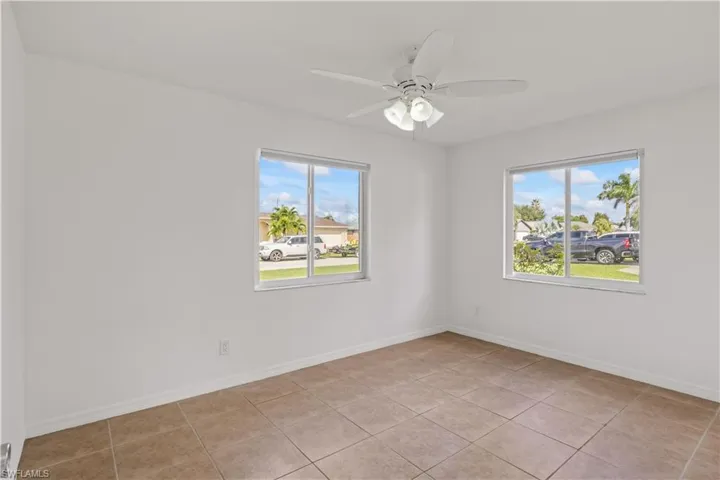 Spare room with light tile patterned flooring, plenty of natural light, and a ceiling fan