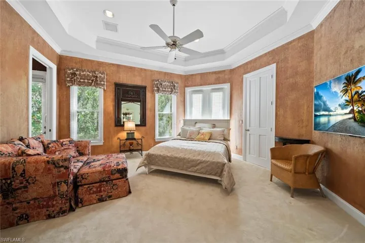 Bedroom with crown molding, a raised ceiling, carpet flooring, and ceiling fan