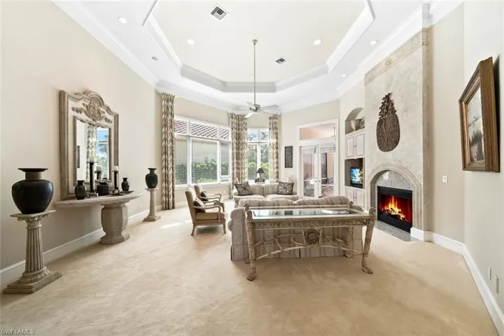 Living room featuring crown molding, light carpet, a fireplace, and ceiling fan