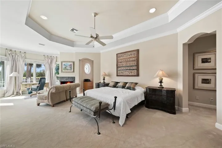 Carpeted bedroom featuring crown molding, a raised ceiling, and ceiling fan