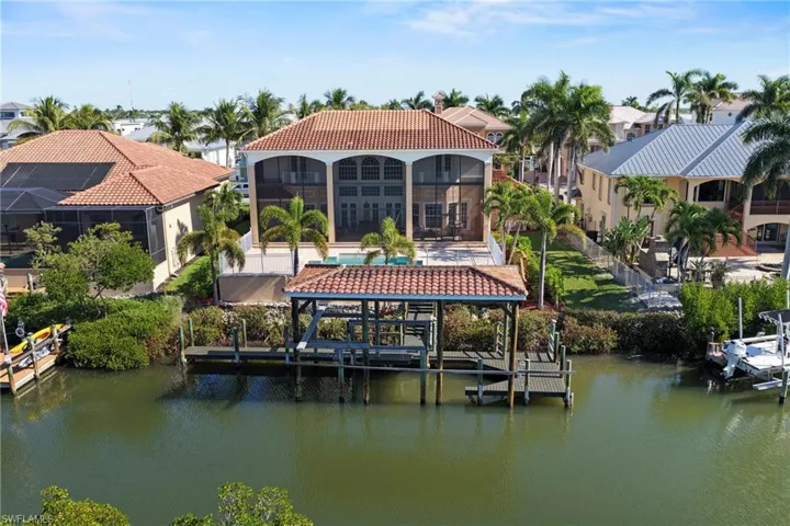 Dock with a water view, boat lift, a swimming pool, and glass enclosure