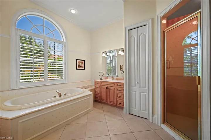 Full bathroom featuring a bath, light tile patterned flooring, a shower stall, vanity, and crown molding