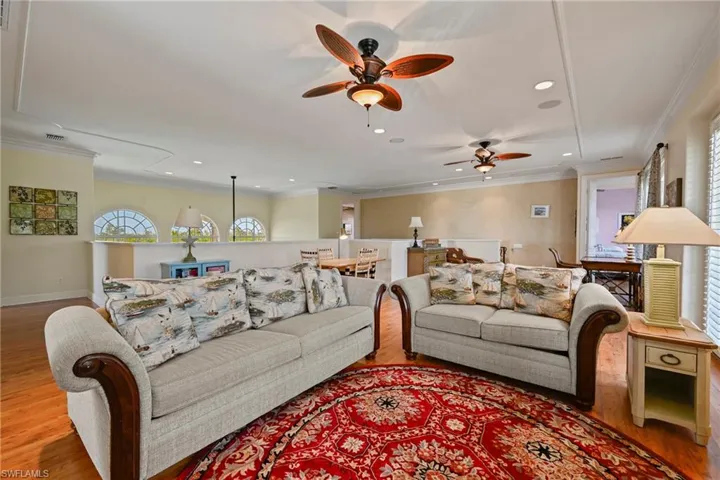 Living area with crown molding, wood finished floors, a ceiling fan, and recessed lighting