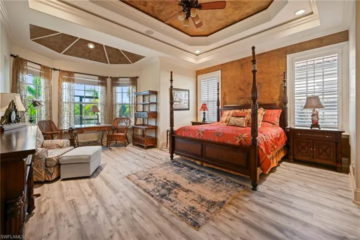 Bedroom featuring crown molding, multiple windows, light wood-style flooring, a raised ceiling, and recessed lighting
