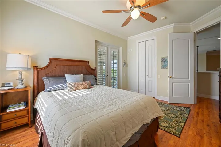 Bedroom featuring light wood-style flooring, crown molding, ceiling fan, a closet, and french doors