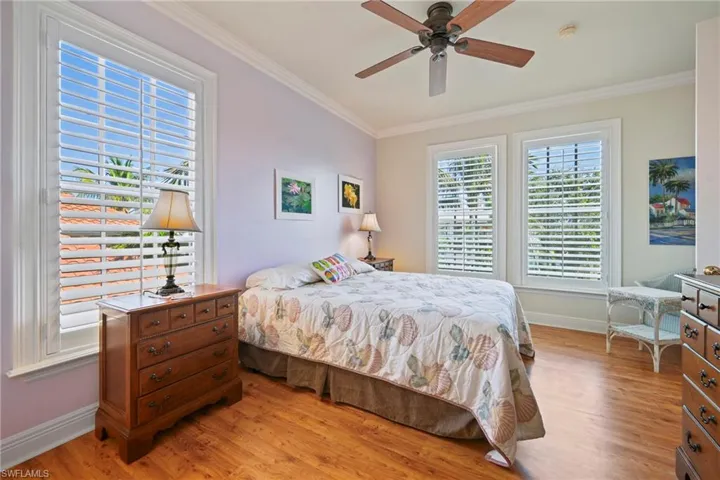 Bedroom featuring ornamental molding, a ceiling fan, and light wood-style flooring