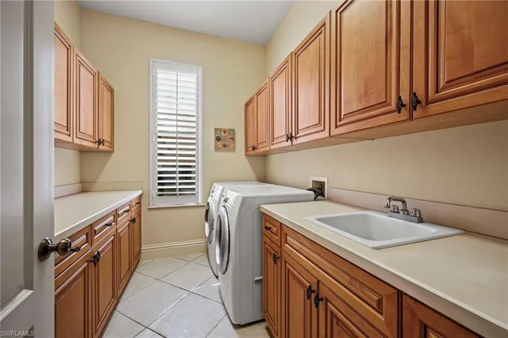 Laundry area with cabinet space, light tile patterned floors, and independent washer and dryer