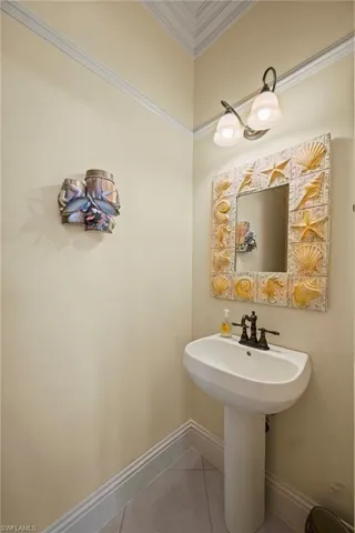 Bathroom with crown molding and light tile patterned floors