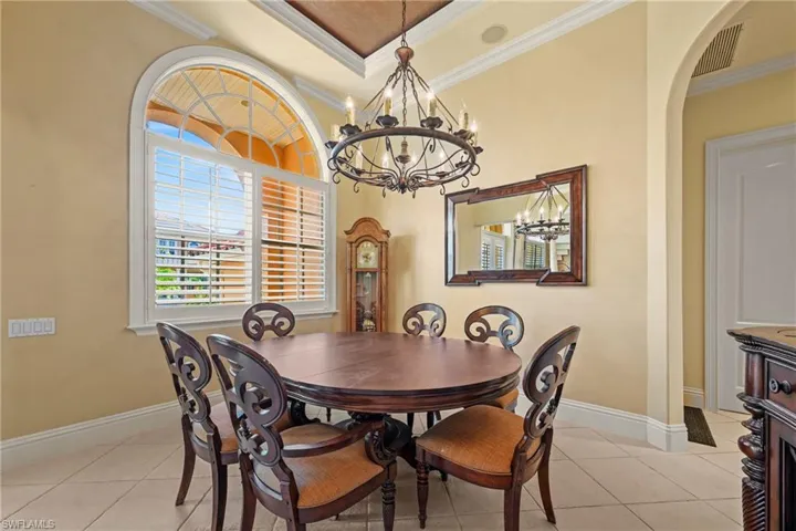 Dining space with light tile patterned floors, crown molding, and a chandelier