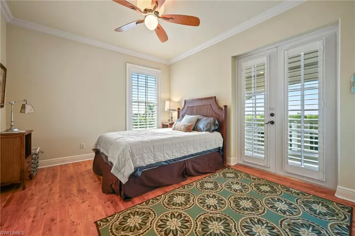 Bedroom featuring french doors, access to exterior, wood finished floors, crown molding, and a ceiling fan