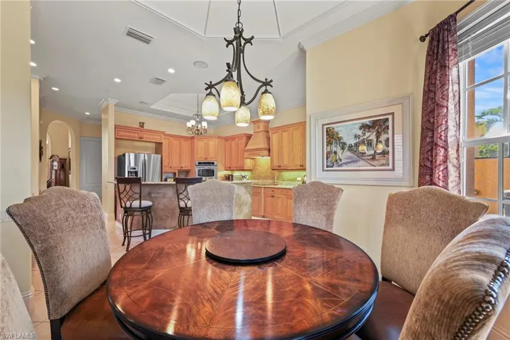 Dining room featuring crown molding, arched walkways, a chandelier, and light tile patterned floors