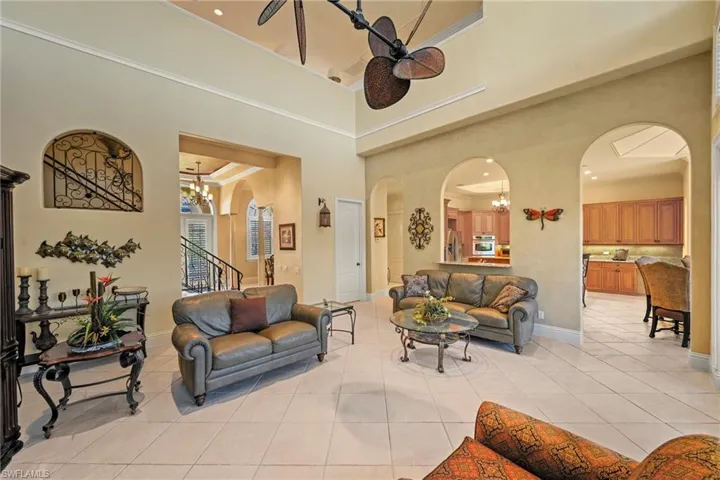 Living room with a chandelier, arched walkways, light tile patterned flooring, a high ceiling, and ornamental molding