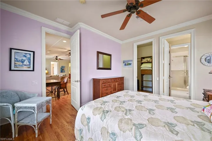 Bedroom featuring light wood-style flooring, crown molding, ensuite bathroom, and ceiling fan