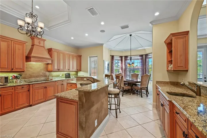 Kitchen featuring a chandelier, light tile patterned flooring, decorative light fixtures, a breakfast bar area, and light stone countertops
