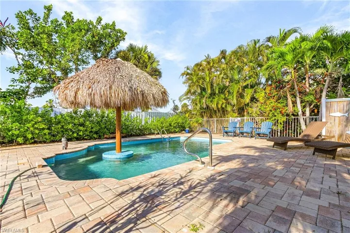 The pool has a built-in ledge and table with tiki cover.