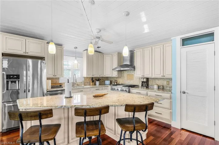 The custom kitchen includes: wood cabinets, stainless appliances, a wine refrigerator, warming tray. and a gas cooktop with electric oven, and a professional vented hood, along with a pantry.