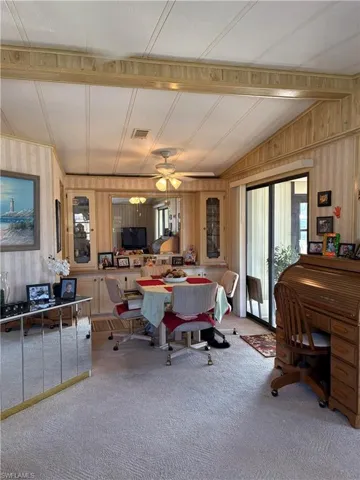 Carpeted dining area with wooden walls and lofted ceiling