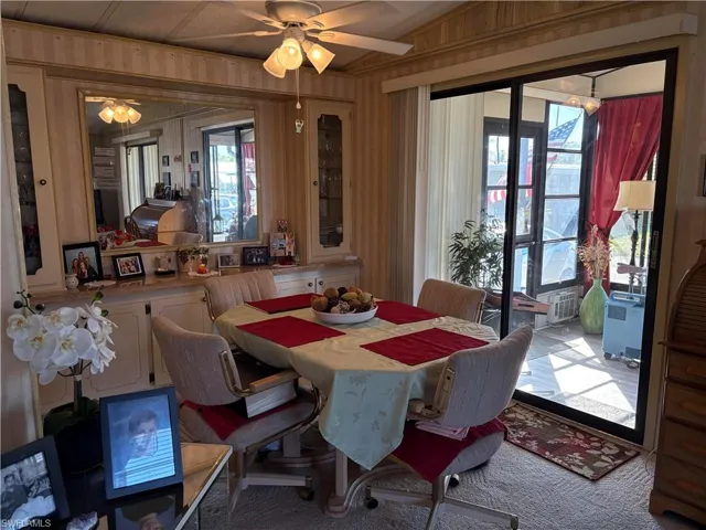 Dining area featuring ceiling fan and wood walls