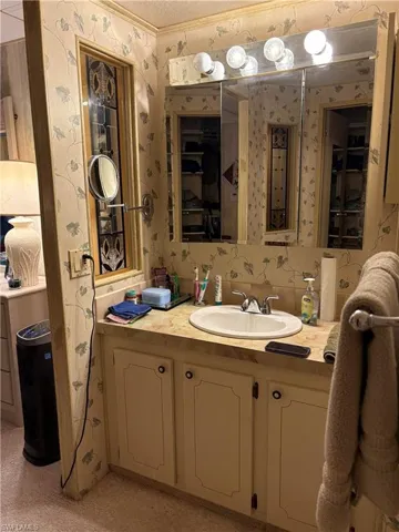 Bathroom featuring a textured ceiling, vanity, and crown molding