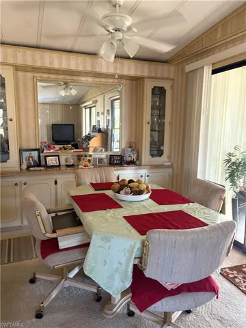 Dining area with ceiling fan, lofted ceiling, wooden walls, and carpet floors