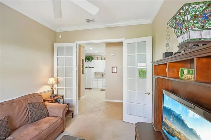 Living room featuring a ceiling fan, light tile patterned floors, baseboards, ornamental molding, and visible vents