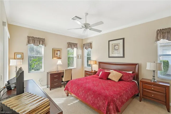 Bedroom with multiple windows, light colored carpet, and ornamental molding