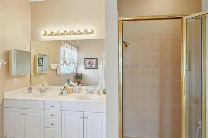 Bathroom featuring a sink, double vanity, and a shower stall