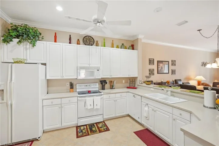 Kitchen with light countertops, white cabinets, a sink, and white appliances
