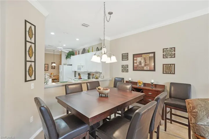 Dining space featuring baseboards, ornamental molding, visible vents, recessed lighting, and ceiling fan with notable chandelier