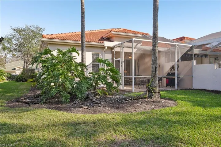 Back of house with a lanai, a lawn, a patio area, and a tile roof