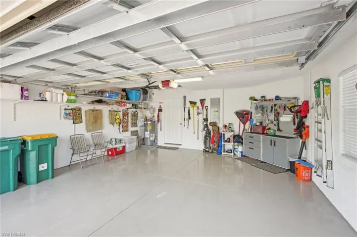 Garage featuring electric panel, a garage door opener, and water heater