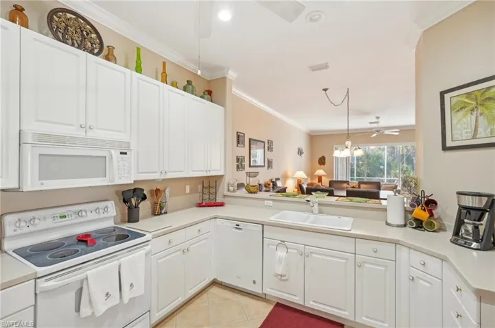Kitchen featuring light countertops, a sink, a peninsula, white appliances, and white cabinetry