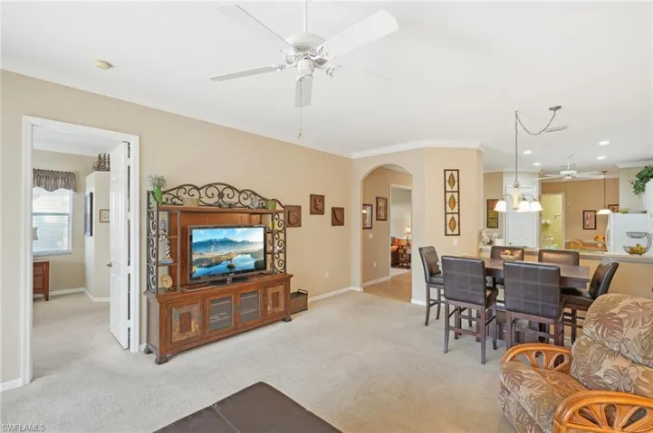 Living room featuring arched walkways, light carpet, and crown molding