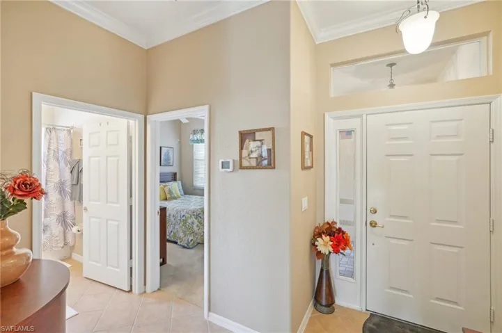 Foyer with baseboards, light tile patterned floors, and crown molding
