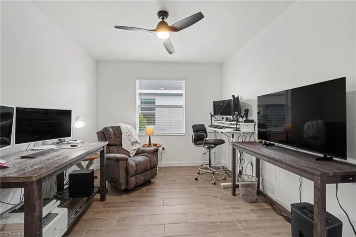 Room featuring wood-look tile flooring, white painted walls, and a ceiling fan with integrated lighting
