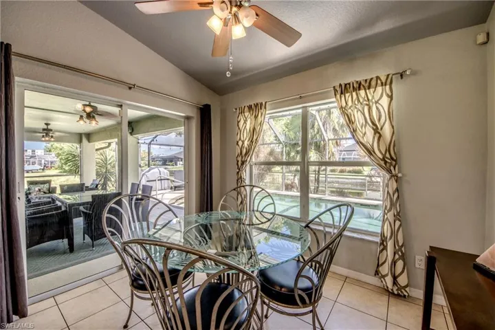 Dining area featuring vaulted ceiling, light tile patterned flooring, a ceiling fan, and a textured ceiling