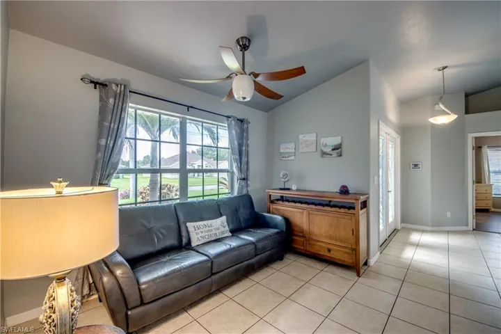 Living area with a ceiling fan, lofted ceiling, and light tile patterned flooring