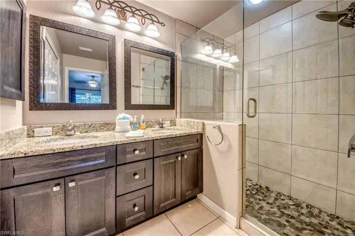Full bath with a shower stall, double vanity, and tile patterned floors